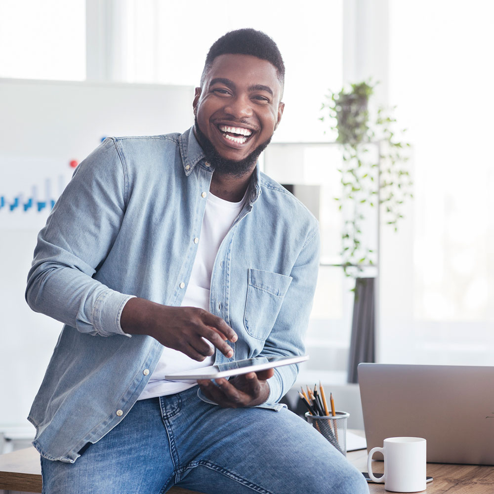 Cheerful black employee using digital tablet in office and laughing