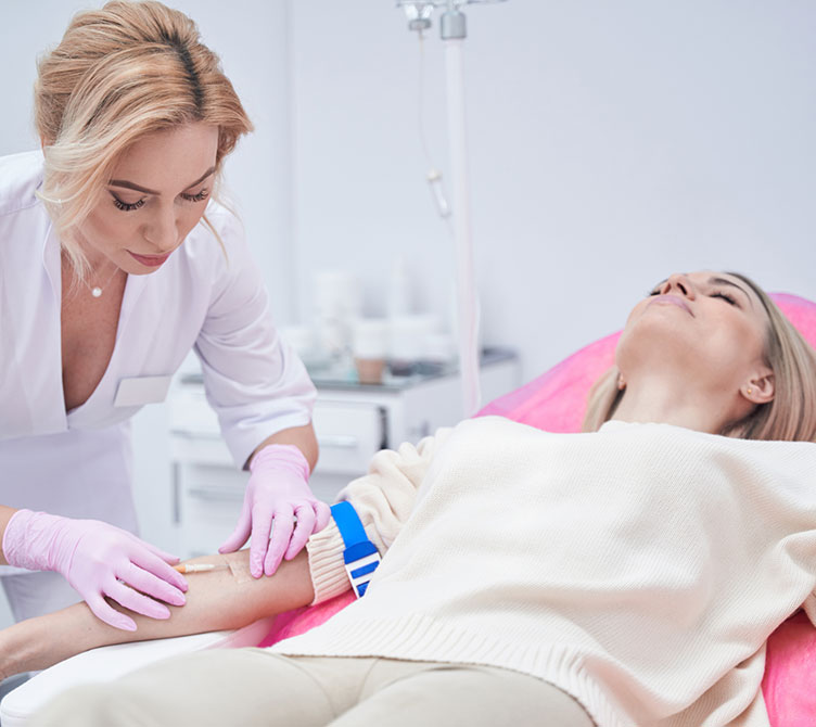 Experienced beauty clinic doctor in nitrile gloves securing catheter in patient vein with adhesive tape.