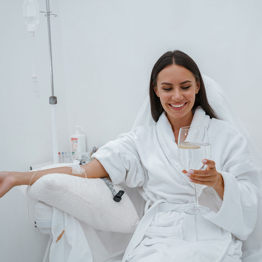 Woman in white bathrobe drink water during medical procedure in beauty clinic. High quality photo.